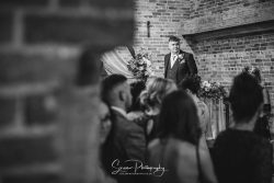donington park farmhouse wedding photography groom waiting for his bride in main barn ceremony room